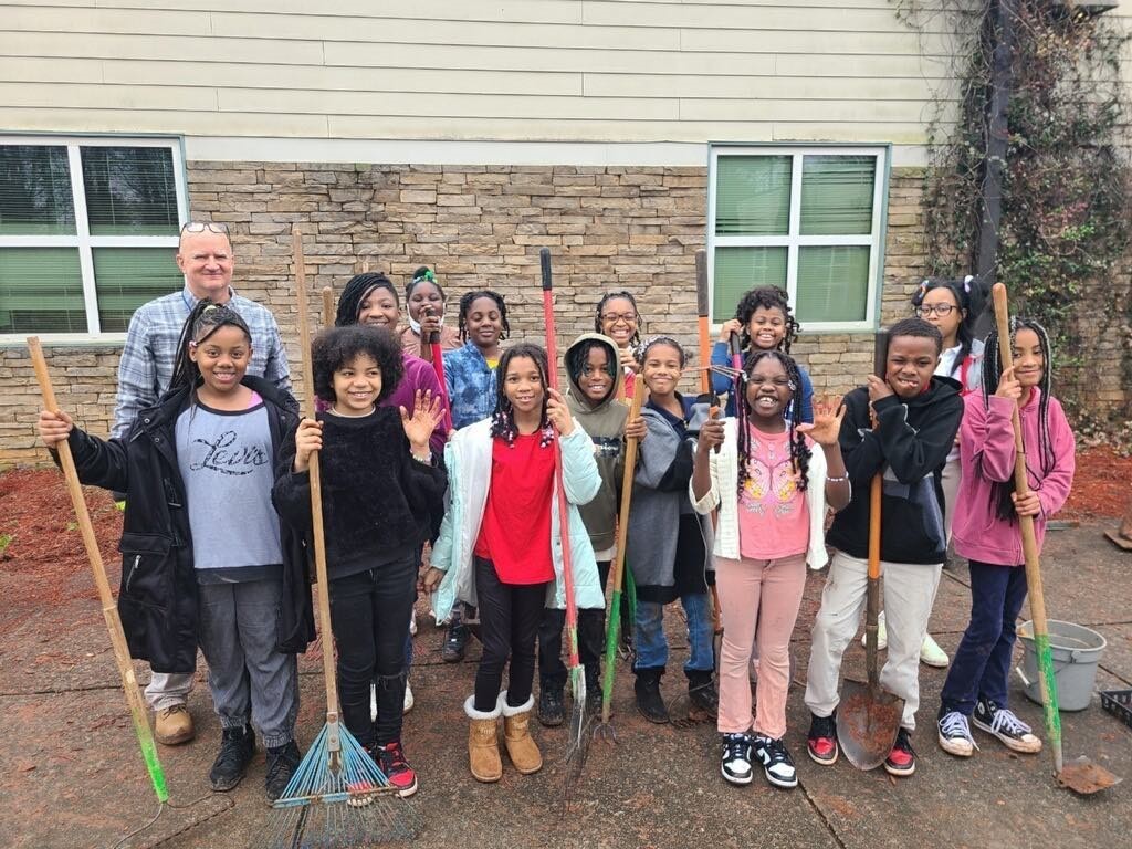 A group of 4th grade students with gardening tools